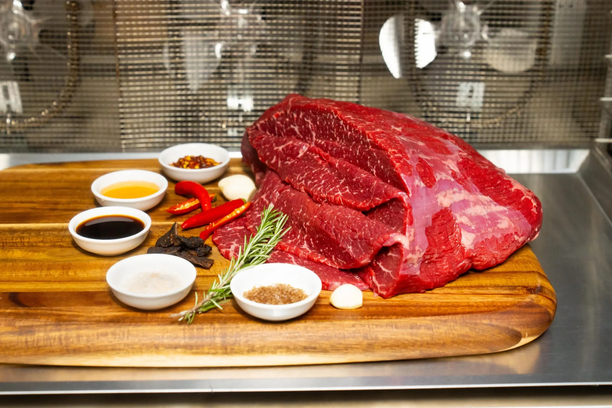 Whole marbled wagyu on the block with the marinade laid out beside it.